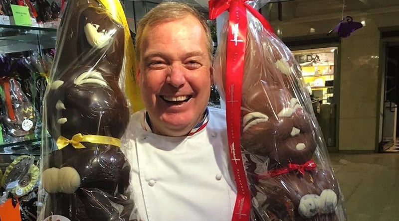 Chef Jacques Torres holding two large chocolate bunnies