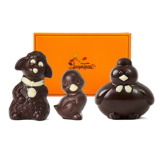 Three chocolate animal figurines in front of a Jacques Torres box.