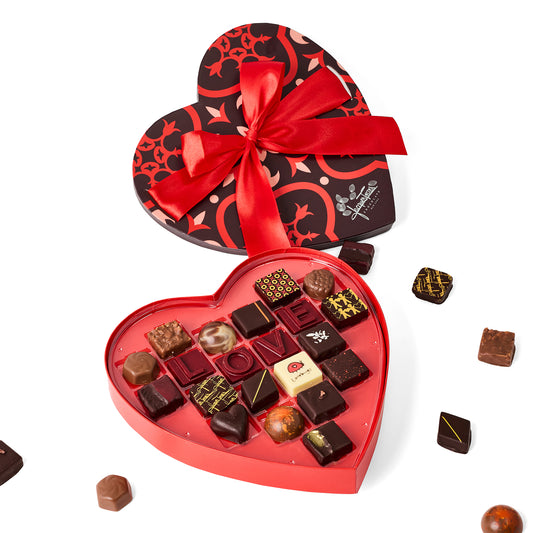 Heart-shaped chocolate box with a red ribbon on a white background