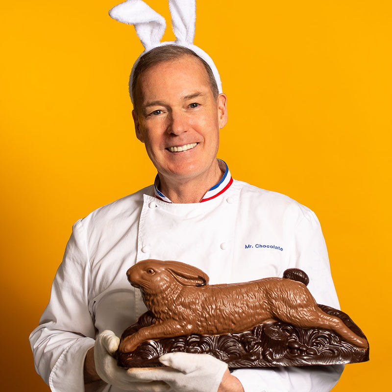 Chef Jacques Torres holding larger running easter rabbit in milk and dark chocolate